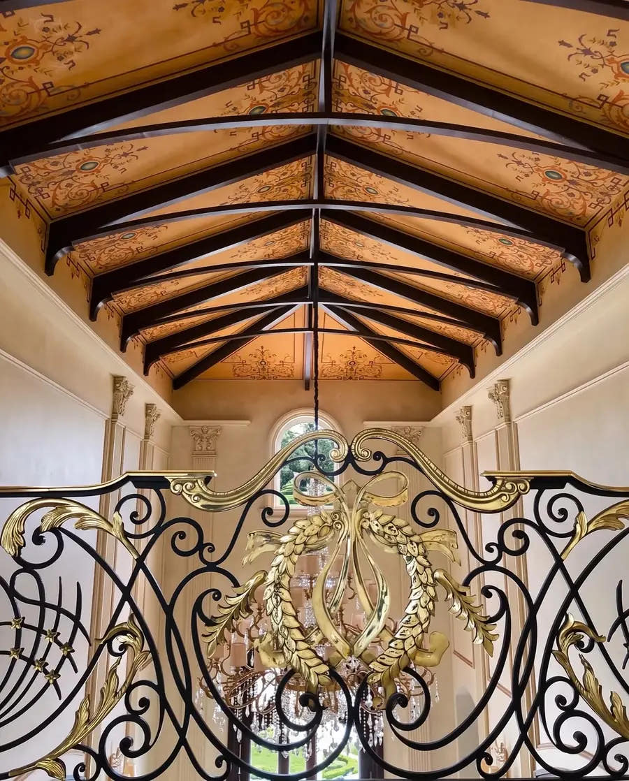 Painted ceiling with dark beams above an ornate railing